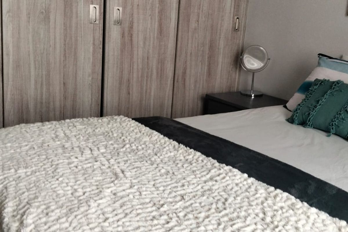 A bedroom featuring floor-to-ceiling built-in cupboards with a wood-grain finish.