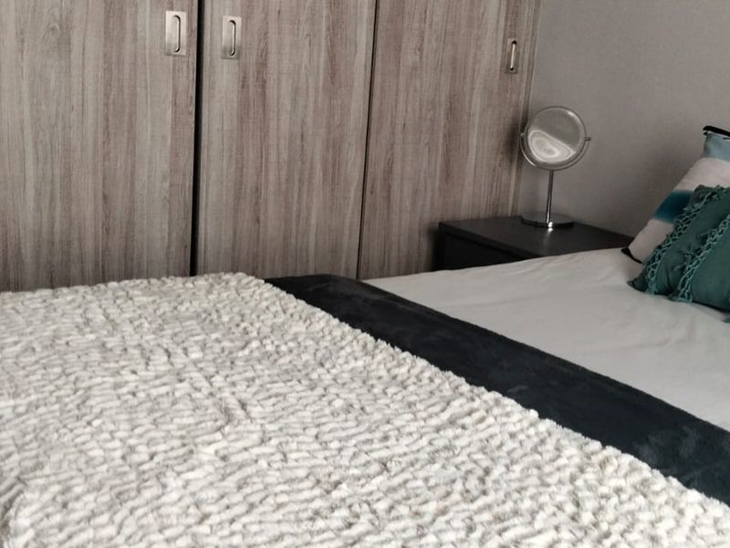 A bedroom featuring floor-to-ceiling built-in cupboards with a wood-grain finish.