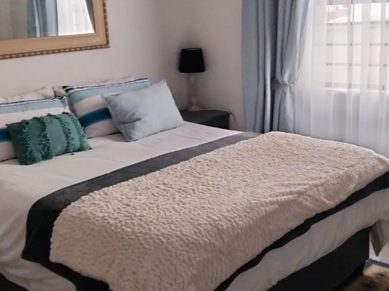 A cozy bedroom featuring neutral walls, a window with curtains, and space for a double bed.