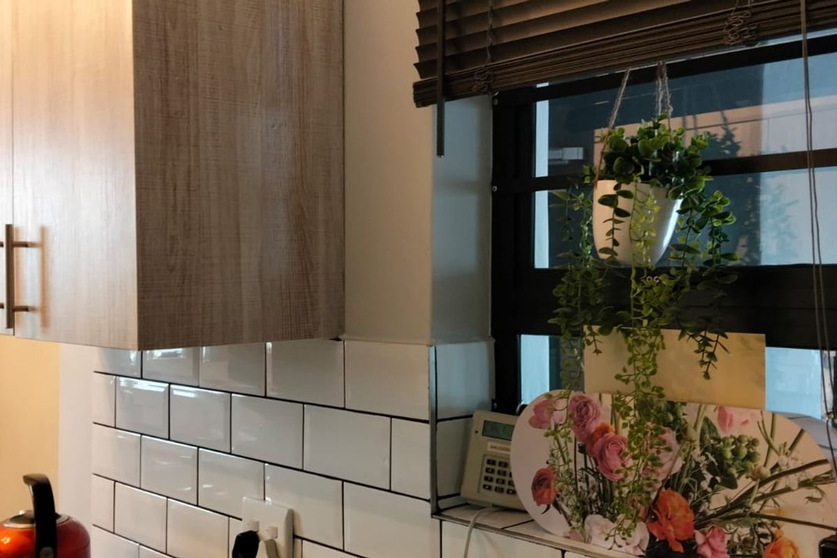 A modern kitchen area featuring clean white subway tile backsplash and contemporary wood-look cabinetry.