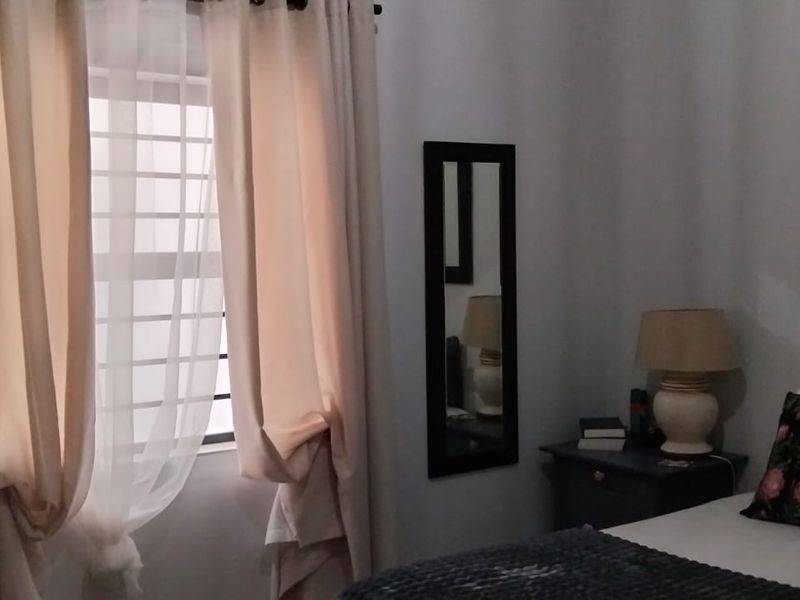 A bedroom featuring a window with curtains and neutral wall finishes.