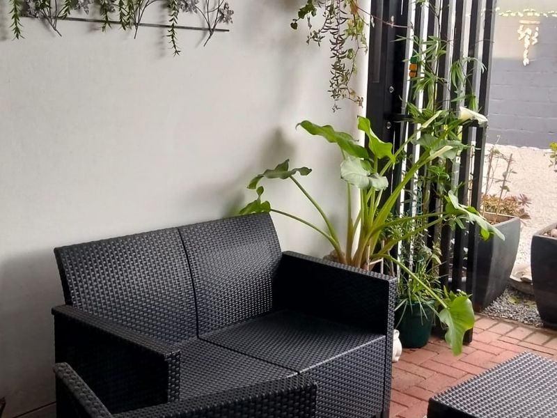 A covered patio area featuring brick paving and a metal security gate, providing a transition to the outdoor garden space.