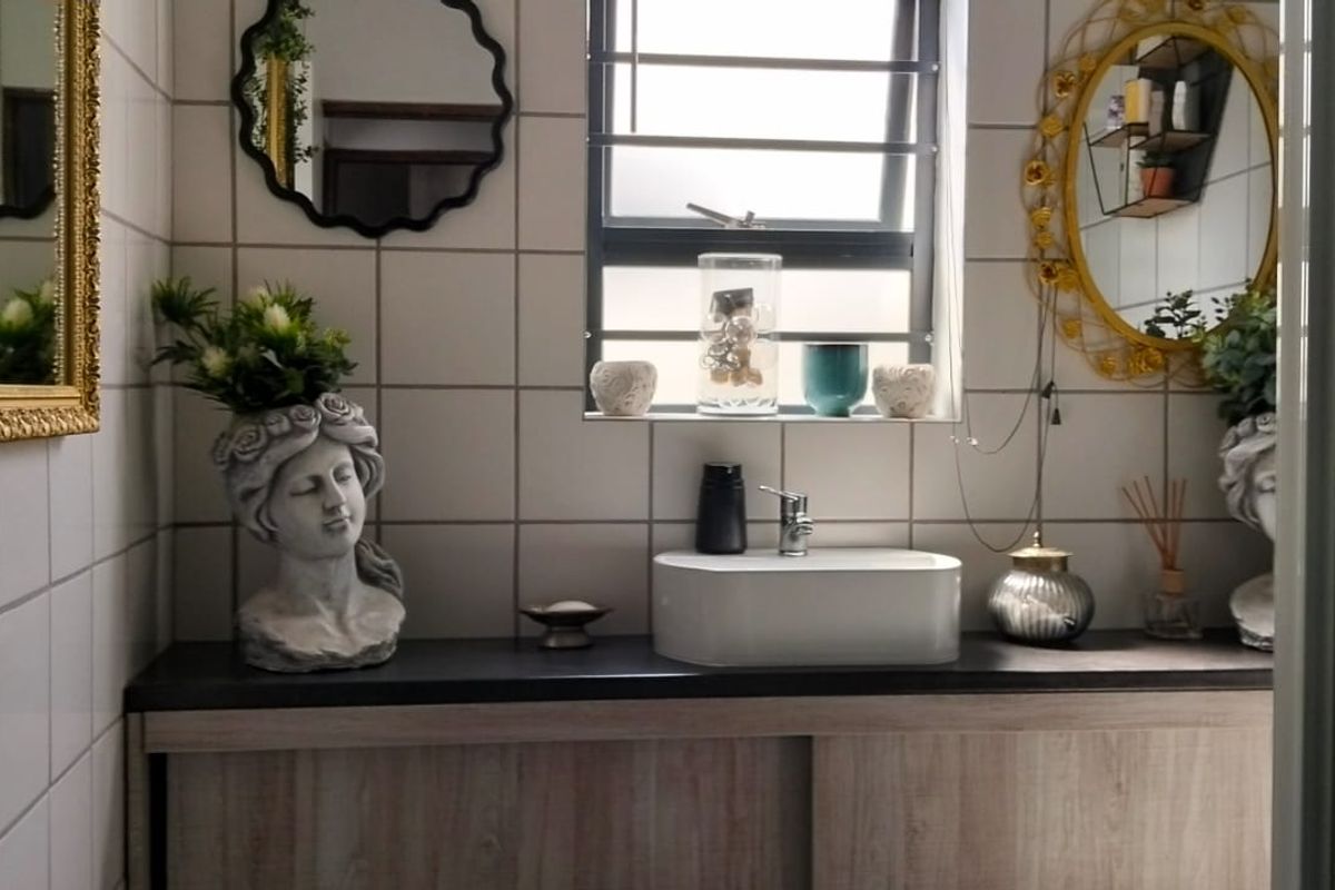 A well-maintained bathroom featuring a modern vessel sink, wood-finish vanity cabinet, and clean white wall tiling.