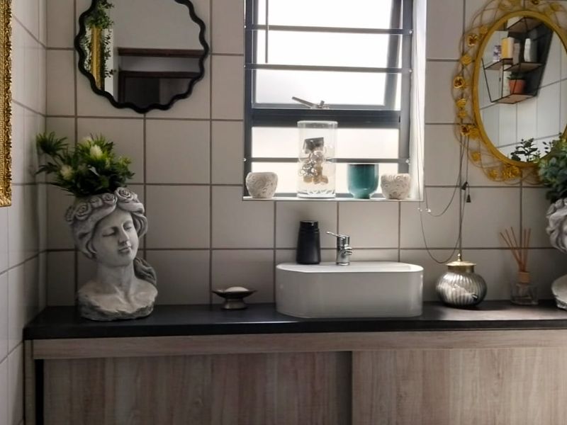 A well-maintained bathroom featuring a modern vessel sink, wood-finish vanity cabinet, and clean white wall tiling.