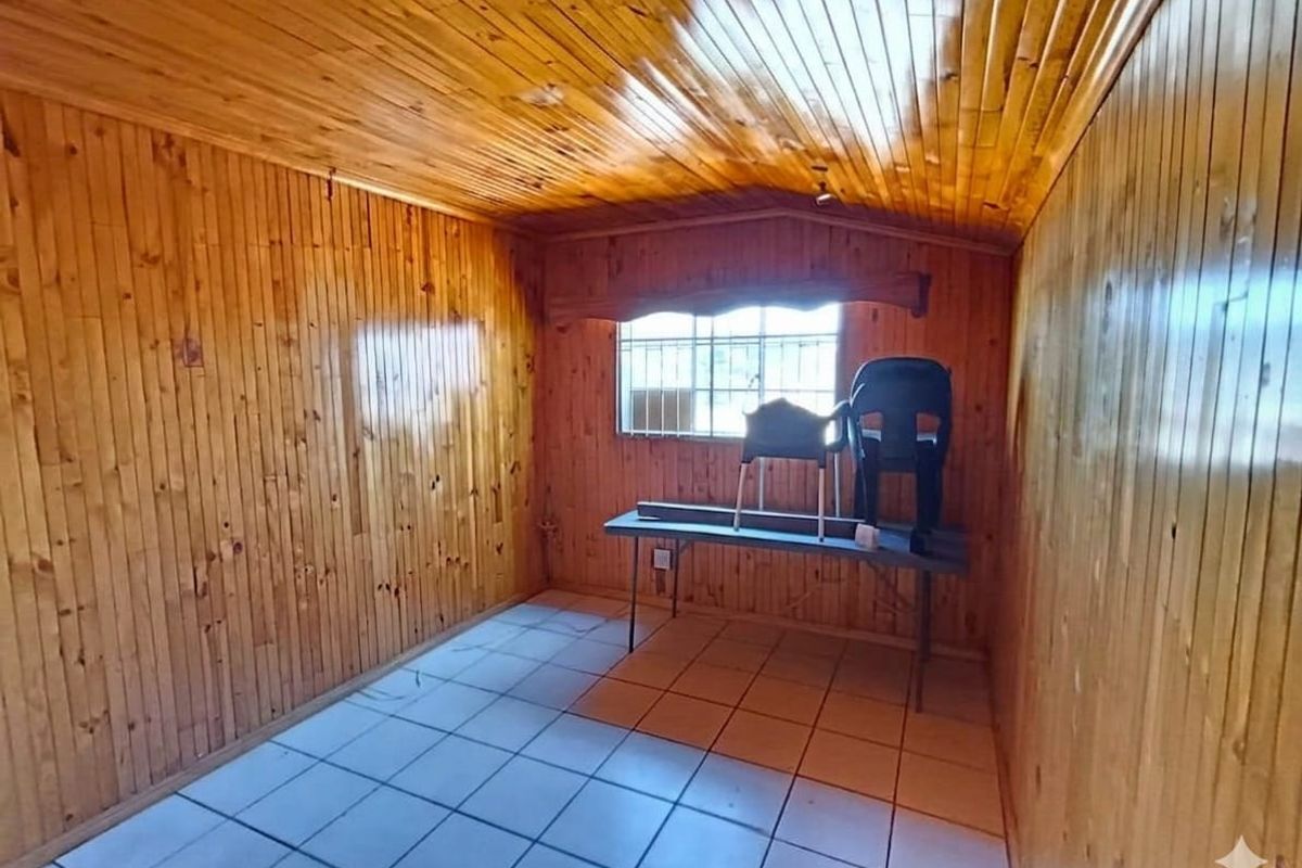 A bedroom featuring extensive timber wall and ceiling cladding with ceramic floor tiles and security bars on the window.