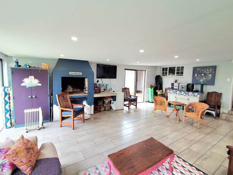 Spacious living area featuring a built-in braai, tiled flooring, and recessed downlights, providing a versatile space for indoor entertaining.