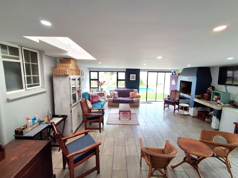 Spacious open-plan living area featuring a built-in fireplace, skylight, and large sliding doors providing direct access to the pool area.