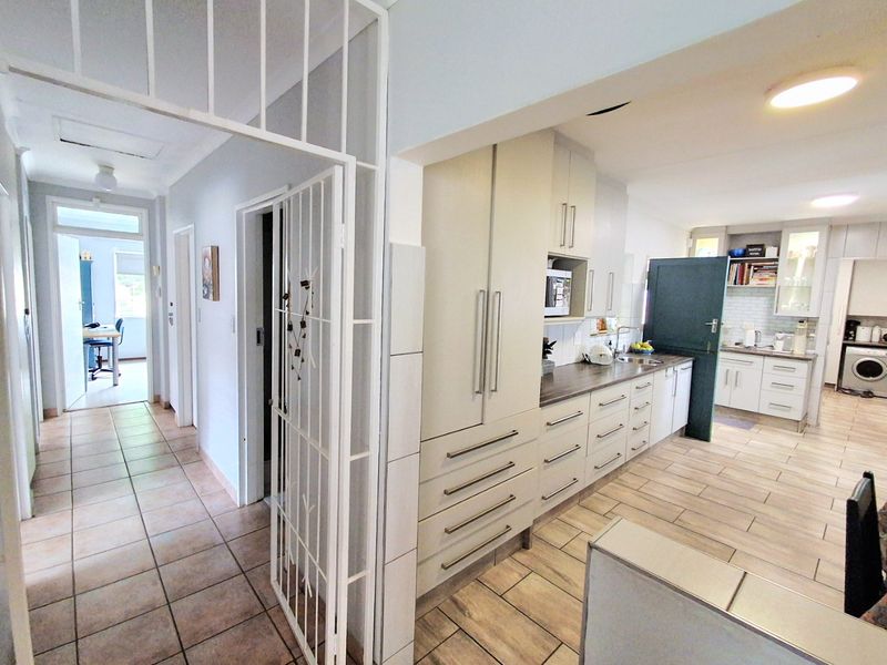 Open-plan kitchen area featuring modern cabinetry, tiled flooring, and a seamless transition into the hallway and adjacent living spaces.