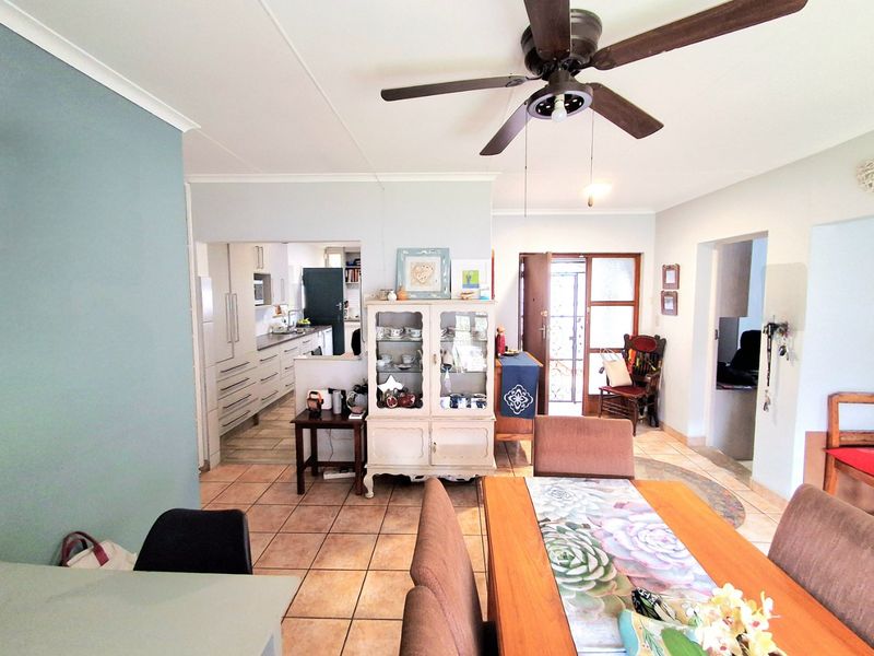 Open-plan living and dining area featuring tiled flooring, a ceiling fan, and a view through to the adjacent kitchen space.