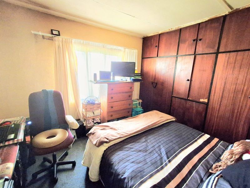 A bedroom featuring built-in wooden cupboards and a window, requiring cosmetic updates to the ceiling and cabinetry to improve the overall aesthetic.