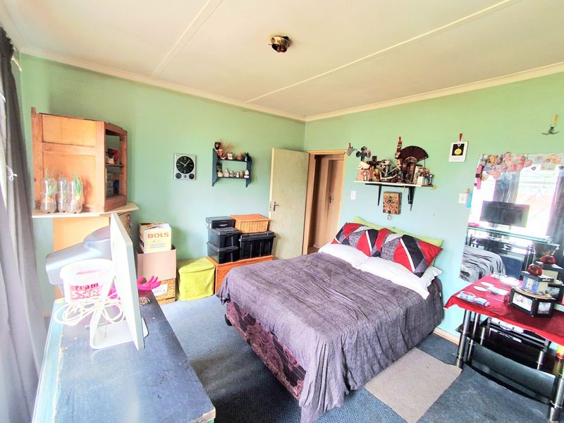 A bedroom featuring green walls and carpeted flooring, offering a functional space with built-in shelving.
