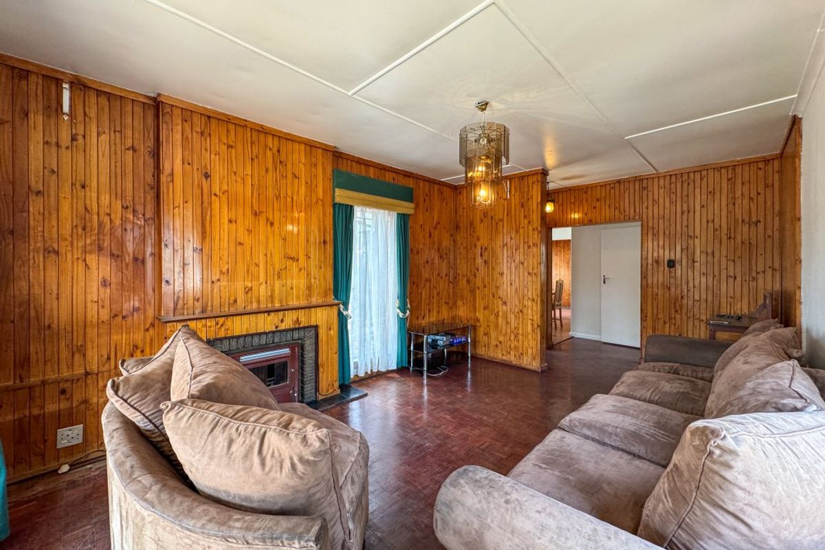Living room featuring traditional wood paneling, parquet flooring, and a built-in fireplace, offering a classic aesthetic with potential for modernization.