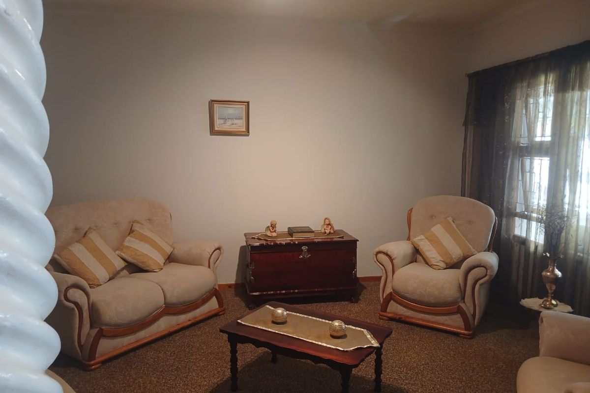 A traditional living room space featuring carpeted flooring and window treatments, offering a neutral foundation for potential interior updates.