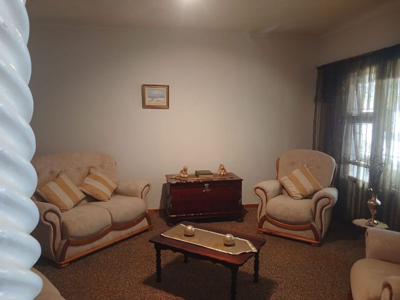 A traditional living room space featuring carpeted flooring and window treatments, offering a neutral foundation for potential interior updates.