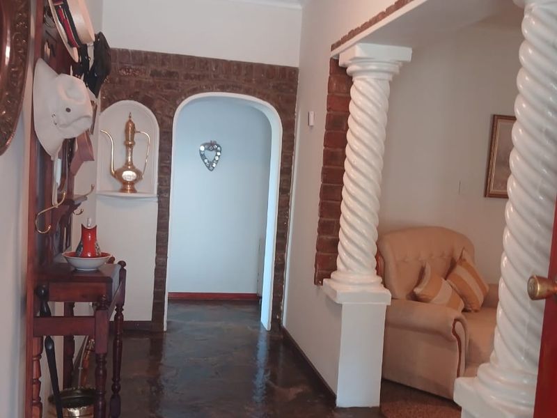 A characterful hallway featuring natural stone flooring, decorative spiral columns, and an arched brick entryway leading into the living space.