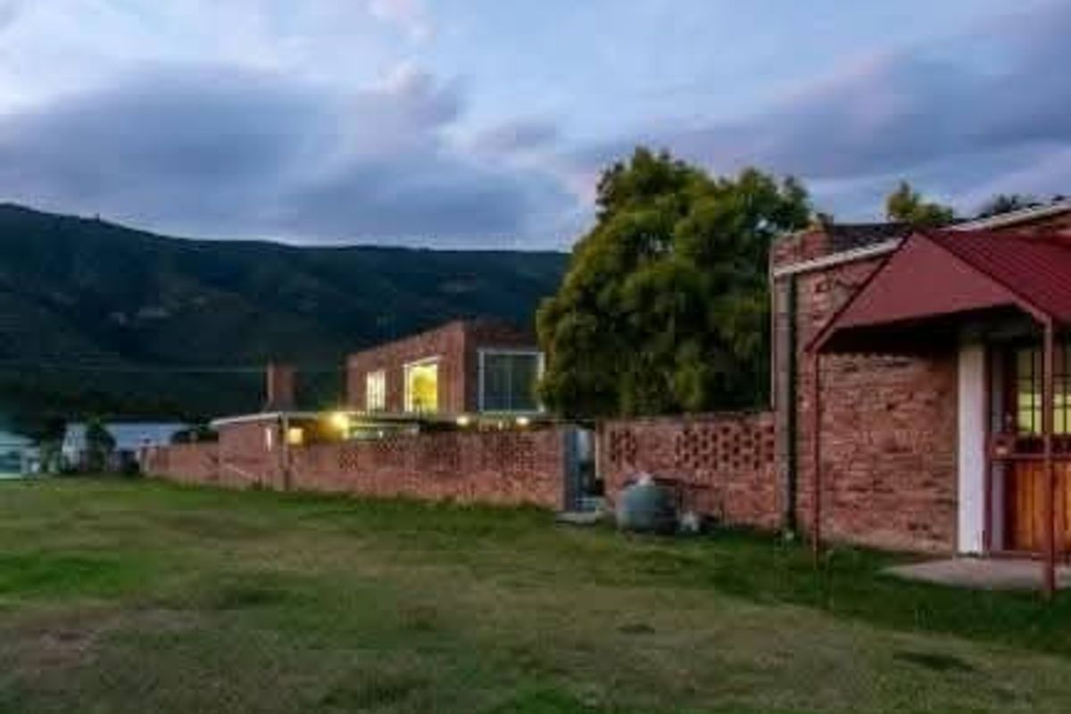 Rear view of the property featuring a brick facade, a covered patio area with a metal awning, and a surrounding brick boundary wall.