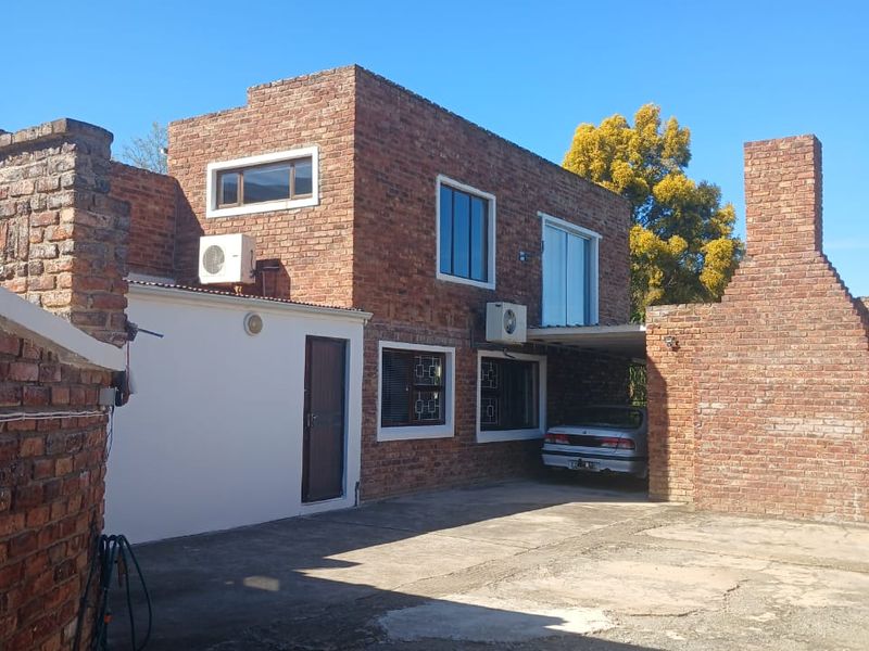 Front exterior view of a two-story exposed brick house featuring a concrete driveway, brick chimney, and installed air conditioning units.