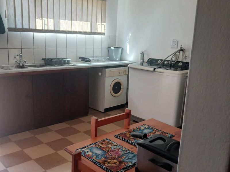 Functional laundry area featuring a double sink, tiled backsplash, and built-in cabinetry with checkered flooring.