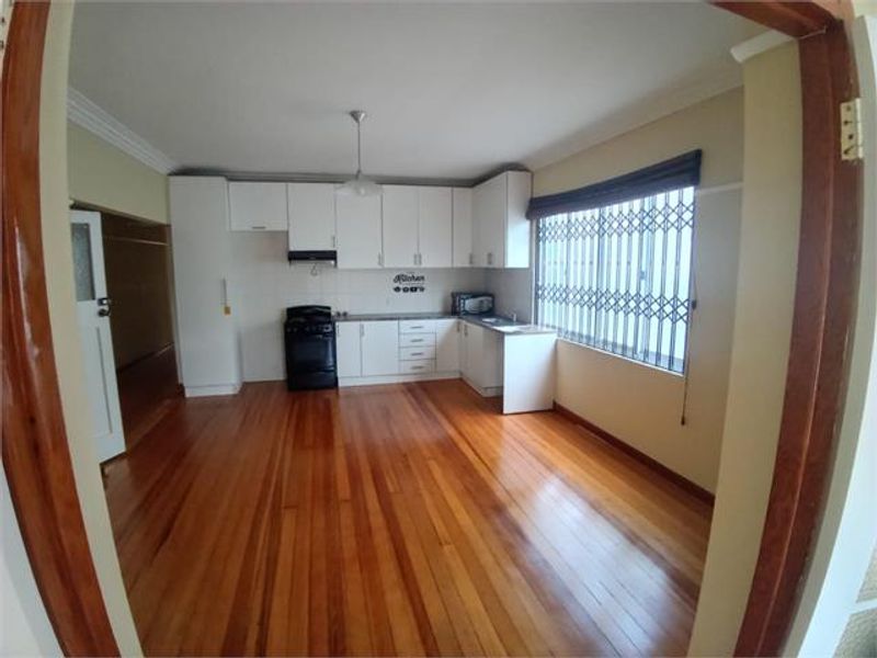 A functional kitchen featuring white cabinetry, hardwood flooring, and a freestanding stove, offering a clean and bright space ready for personalization.
