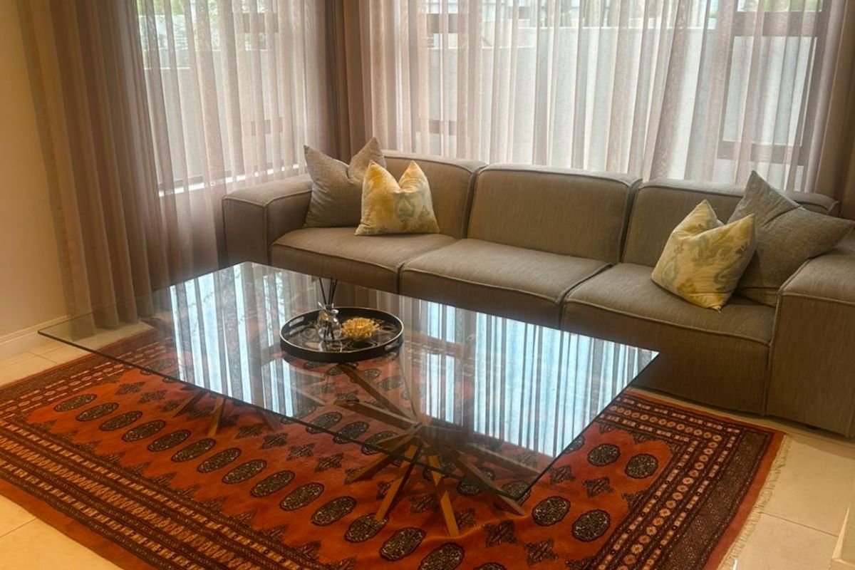 A bright and well-maintained living room featuring large windows with floor-to-ceiling curtains, recessed downlighting, and polished tiled flooring.