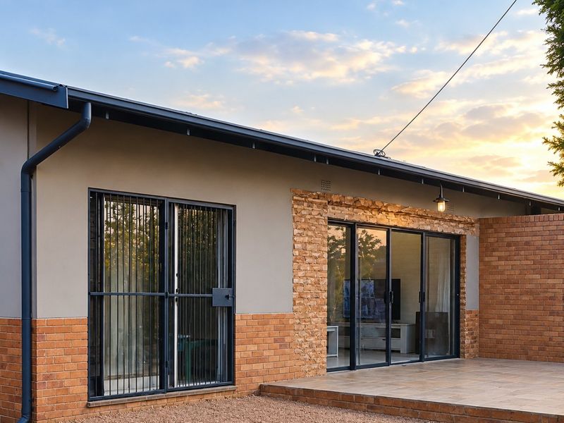 Rear view of the house featuring a tiled patio, sliding glass doors, and a combination of brick and rendered wall finishes.