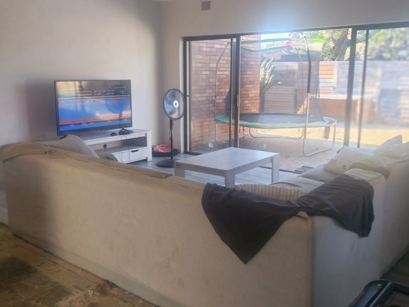 Living room featuring large sliding glass doors leading to the rear garden, with recessed lighting and unfinished flooring requiring completion.