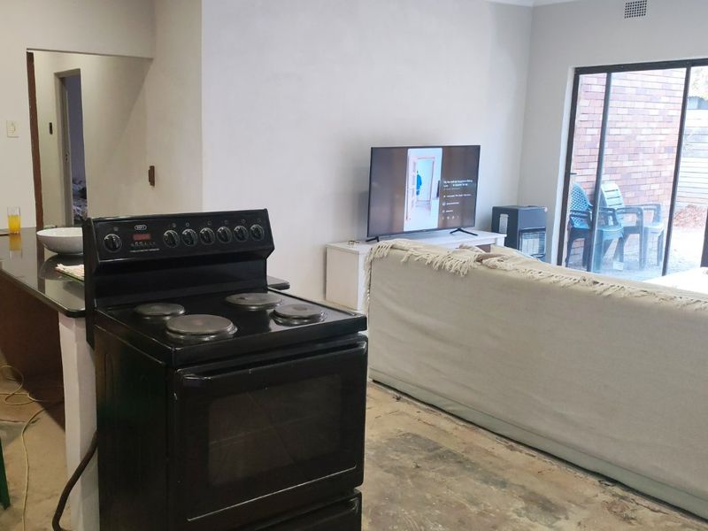 Open plan living and kitchen area featuring a freestanding stove, granite countertops, and sliding door access to the patio, currently undergoing renovation.