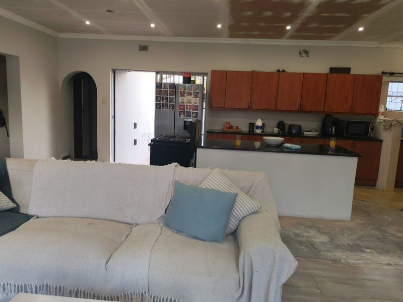 Open plan living and kitchen area featuring wooden cabinetry and a kitchen island, currently undergoing renovation with unfinished ceiling and flooring.