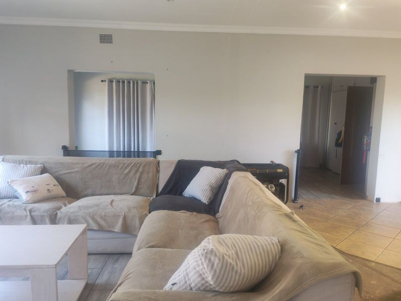 A living room area featuring ceramic floor tiles, recessed lighting, and coved cornicing, providing a functional space with neutral wall finishes.