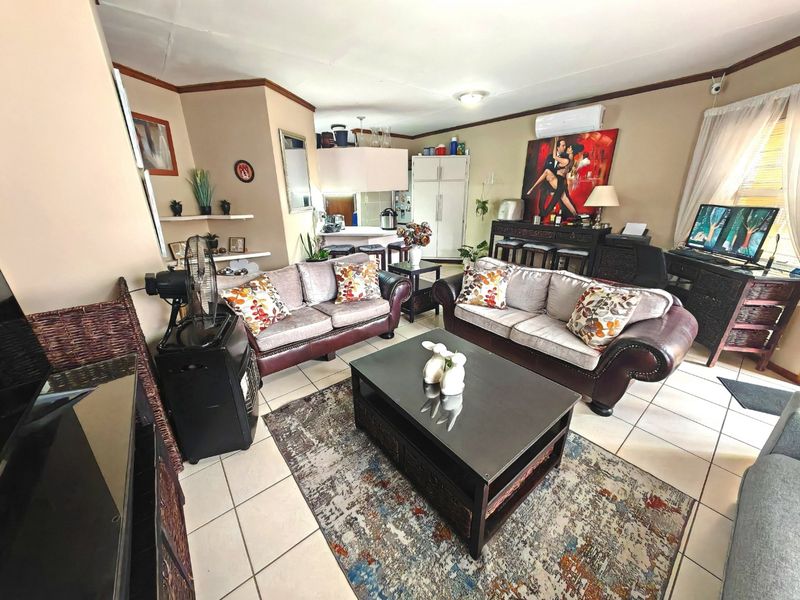 Open-plan living area featuring tiled flooring, a split-system air conditioner, and an integrated kitchen space with cabinetry and a breakfast island.