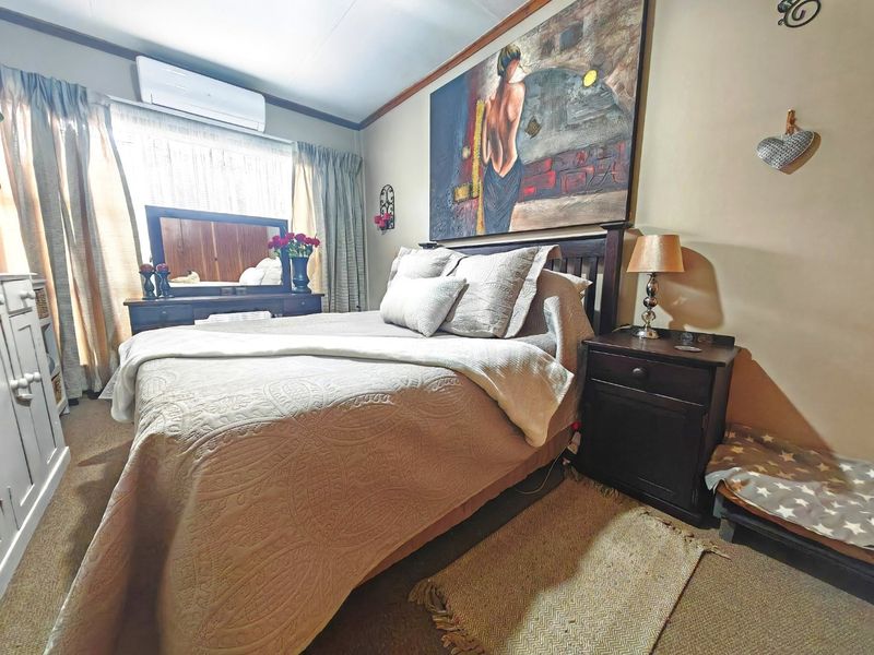 A cozy bedroom featuring carpeted flooring and a wall-mounted split-system air conditioner for climate control.