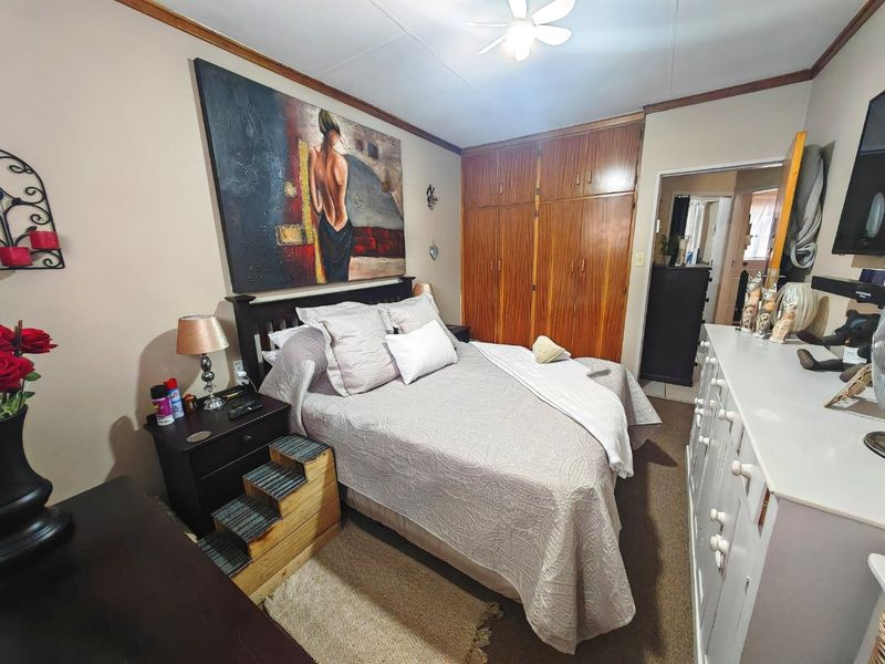 A bedroom featuring built-in wooden cupboards and a ceiling fan, offering a functional space with traditional finishes.