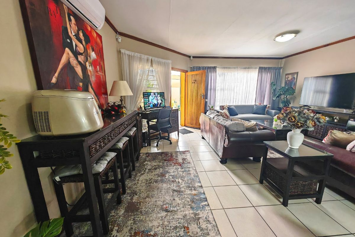 Spacious living room featuring tiled flooring, a split-system air conditioner, and direct access to the exterior through a timber door.