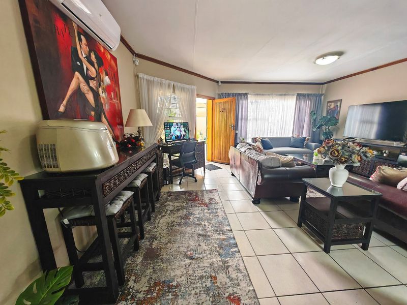 Spacious living room featuring tiled flooring, a split-system air conditioner, and direct access to the exterior through a timber door.