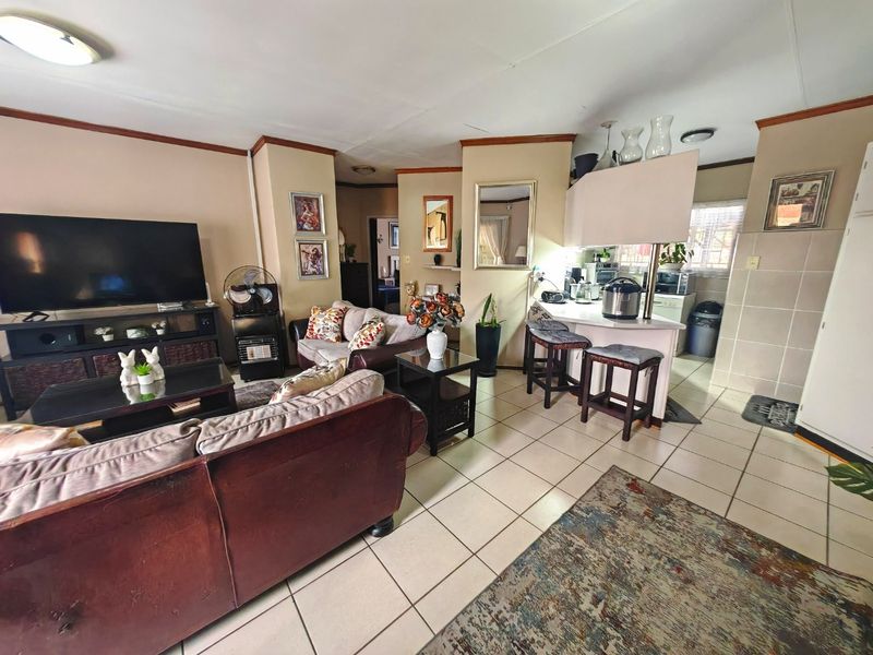 Open plan living and kitchen area featuring tiled flooring and a breakfast bar, offering a functional layout for daily living.