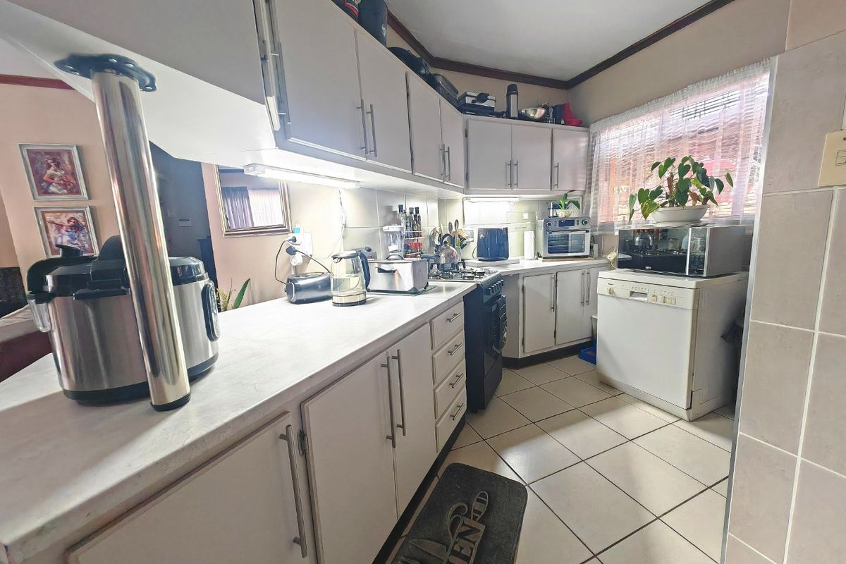 Functional kitchen featuring laminate countertops, ample built-in cabinetry, a gas stove, and tiled flooring, offering a practical layout for daily meal preparation.