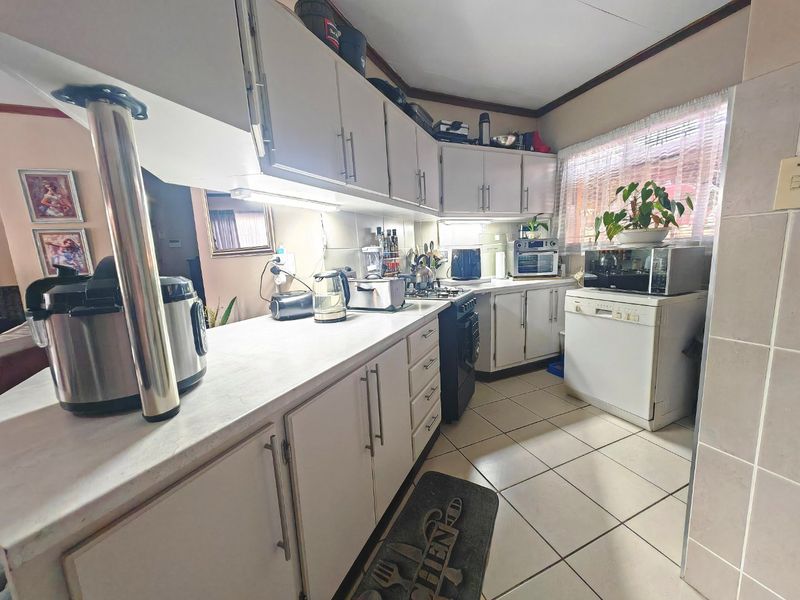 Functional kitchen featuring laminate countertops, ample built-in cabinetry, a gas stove, and tiled flooring, offering a practical layout for daily meal preparation.