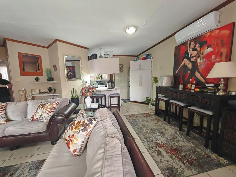 Open-plan living and kitchen area featuring tiled flooring, a breakfast bar, and a wall-mounted split-system air conditioner.