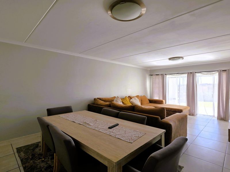 Spacious open-plan living and dining area featuring neutral tiled flooring and large sliding glass doors providing access to the outdoor space.