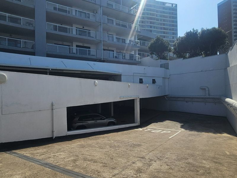 An open-air concrete parking area with retaining walls and access to the apartment building structure.