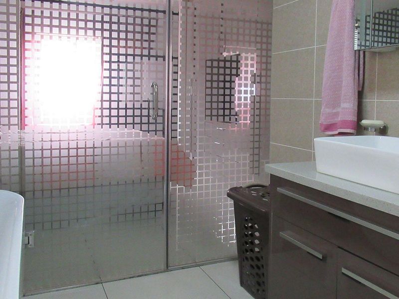 Modern bathroom featuring a freestanding bathtub, glass-enclosed shower, and a sleek vanity with a countertop basin and tiled finishes.