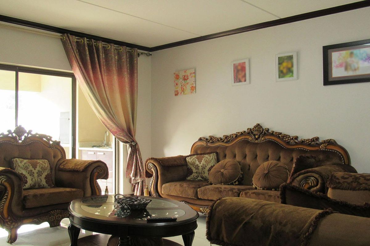 A comfortable living room featuring crown molding and a large sliding glass door that provides access to an outdoor area.