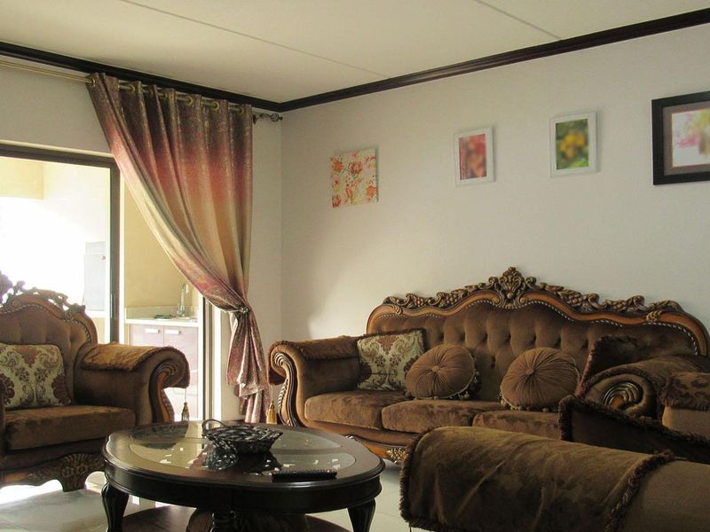 A comfortable living room featuring crown molding and a large sliding glass door that provides access to an outdoor area.