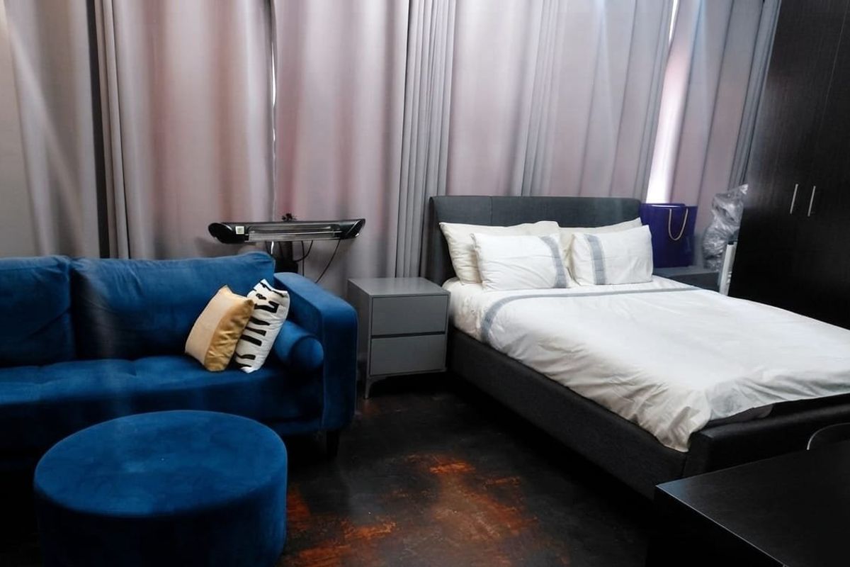 A bedroom featuring dark flooring, a built-in wardrobe, and a wall-mounted heater, offering a functional living space.