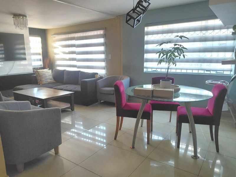 An open-plan living and dining area featuring polished porcelain floor tiles, modern zebra blinds, and contemporary lighting fixtures, creating a bright and functional living space.