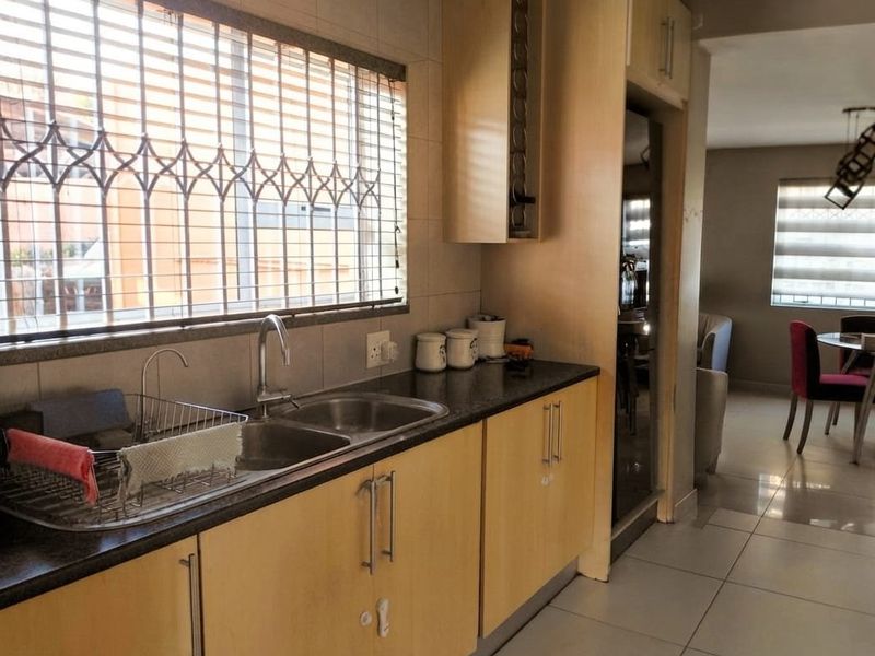 A functional kitchen featuring laminate cabinetry, granite countertops, and a double bowl sink, with a view through to the adjacent dining area.