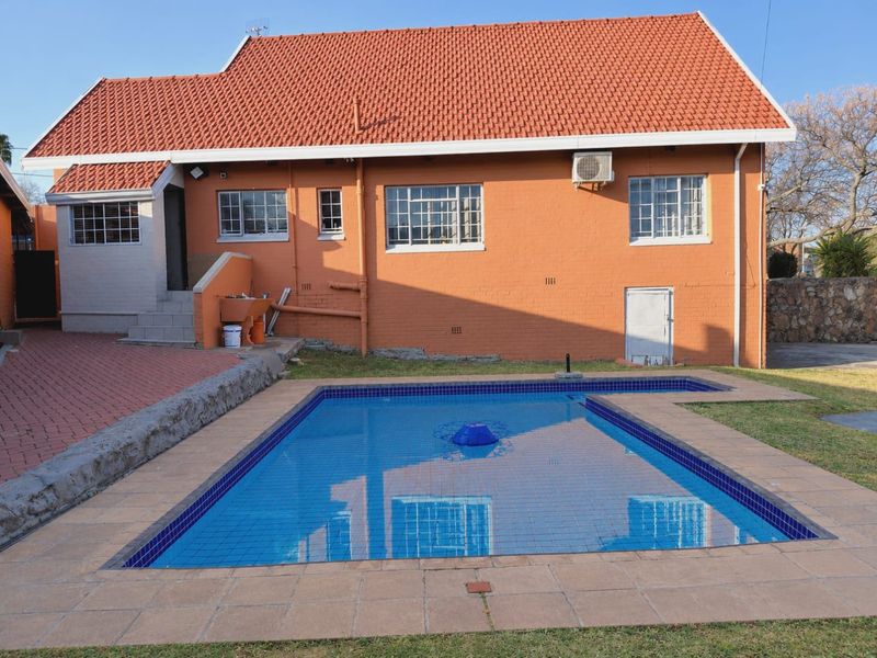 Rear view of the property featuring a swimming pool with tiled surround, brick facade, and terracotta roof tiles.