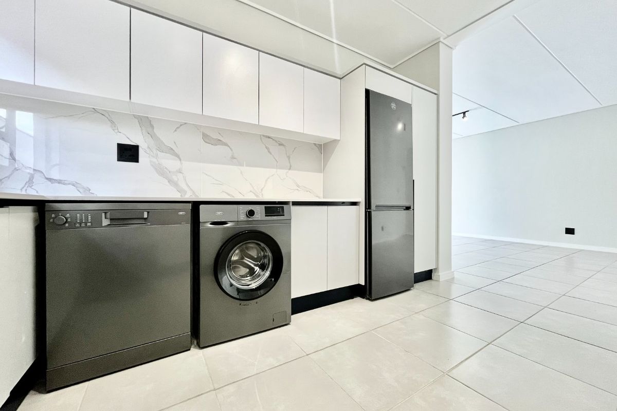 Modern kitchen featuring sleek white cabinetry, marble-look splashback, and tiled flooring, offering a clean and contemporary aesthetic.