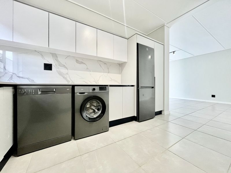 Modern kitchen featuring sleek white cabinetry, marble-look splashback, and tiled flooring, offering a clean and contemporary aesthetic.