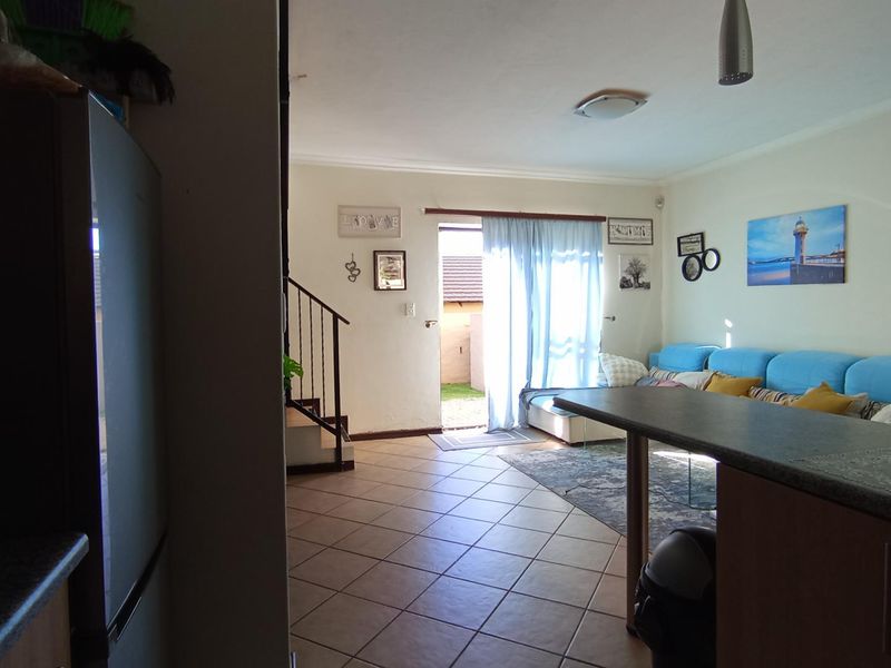 Open plan living area featuring tiled flooring, a breakfast counter, and a sliding glass door providing access to the exterior.